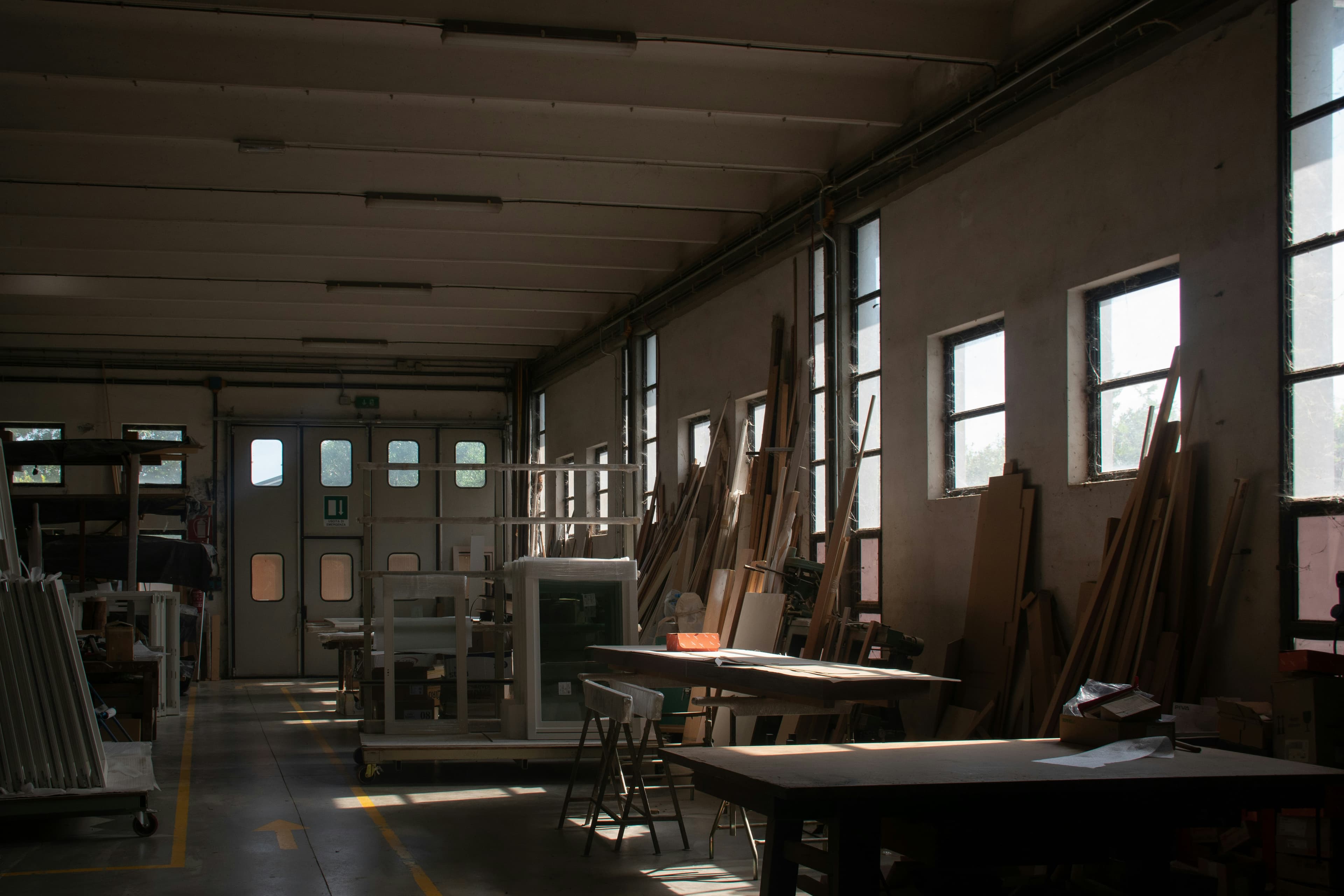 Atmospheric woodworking workshop with timber stock, benches, and window light
